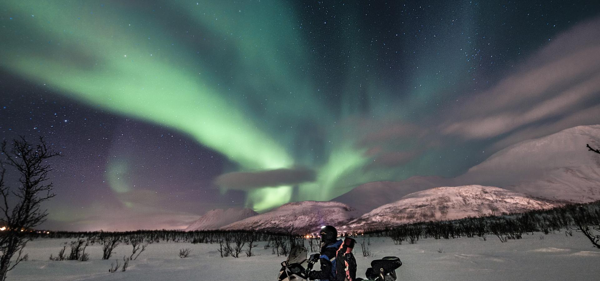 Snowmobiling under the northern lights in the Lyngen Alps, Northern Norway