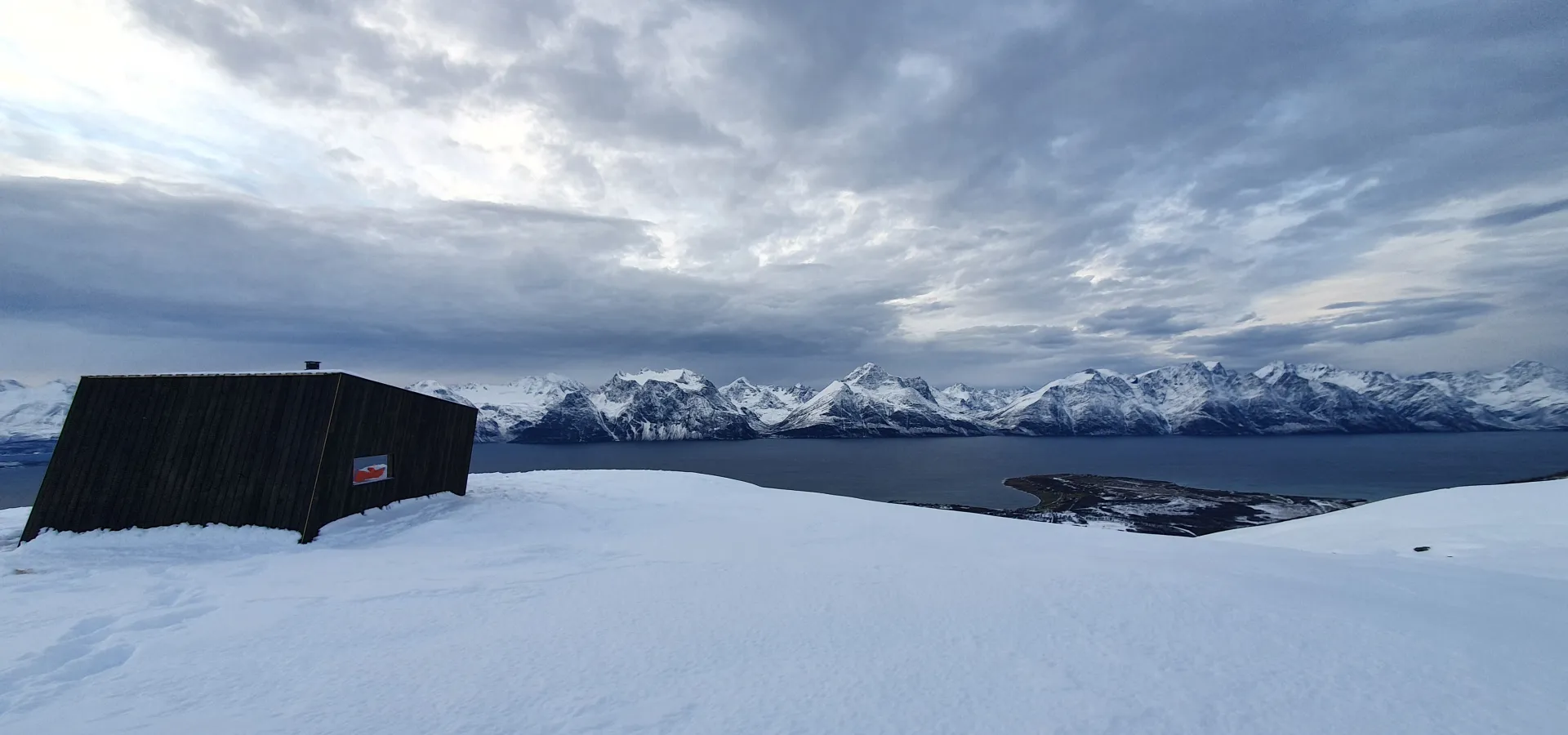 Dagsturhytta på Dalberget om vinteren med Lyngsalpene i bakgrunnen