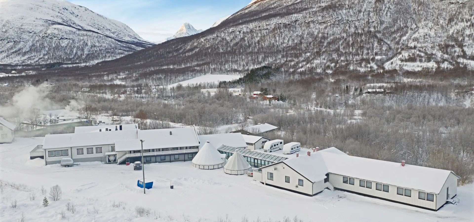 Drone photo of the hotel in the wintertime with fresh snow covering the ground and the mountains in the background