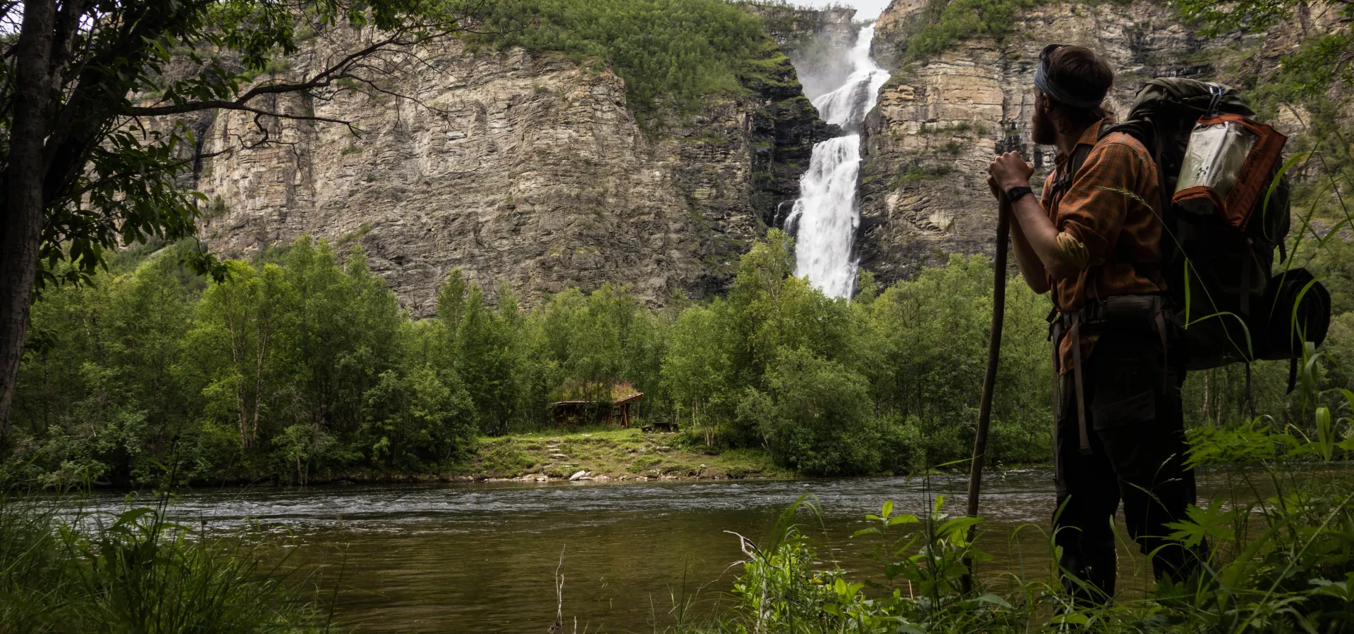 Hiker looking across the river towards a waterfall