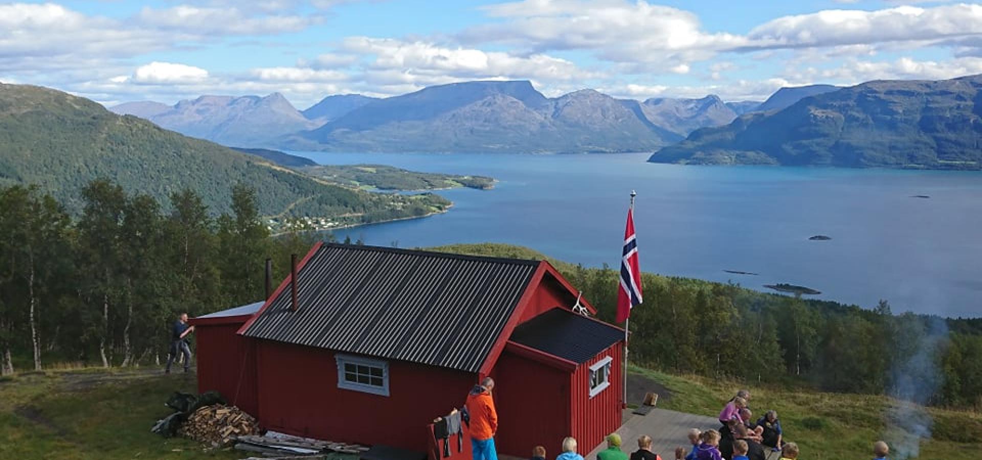 Rød hytte i fjellet med utsikt over fjell og fjorder