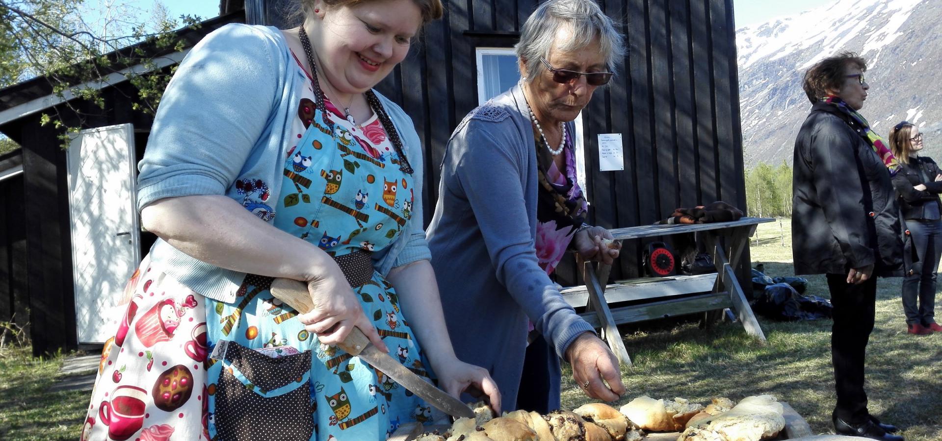 Two women baking bread outdoors