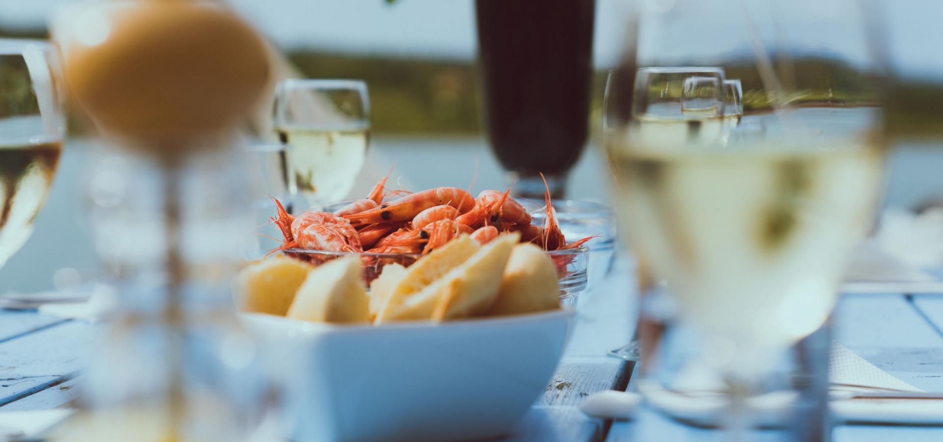 A summer table with glasses of wine, bowls with with bread and shrimps