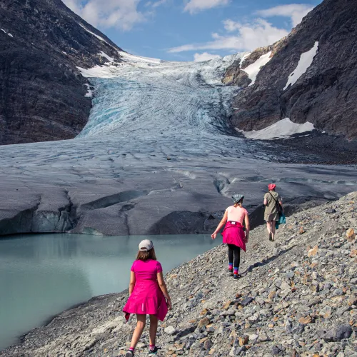 3 persons walking towards the glacier on a rocky ground