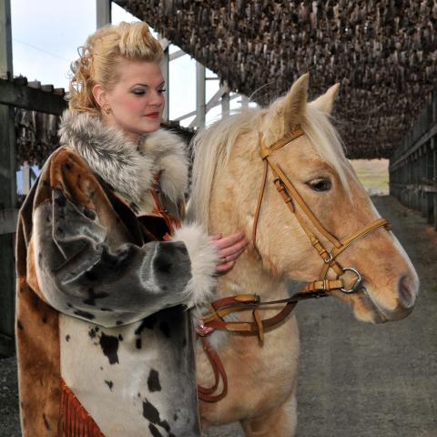 A woman dressed in a fur coat, together with her horse
