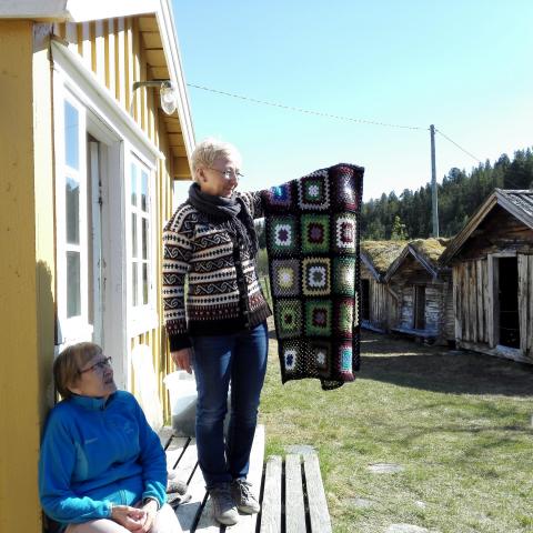 Tørfoss Kven farm in the Reisa Valley in Nordreisa municipality, woman holding a carpet outside the house
