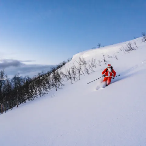 Nisse på ski ned en snødekt fjellside