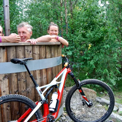 3 people in a hot tub and a mountain bike in  front