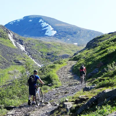 Two mountain bikers heading up a dirt trail in a valley