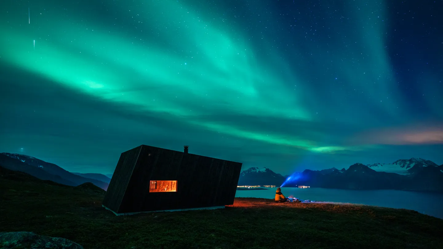 Person enjoying the Northern Lights over the Lyngen Alps in Lyngenfjord, close to Tromsø