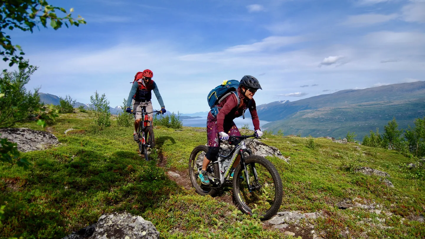 To stisyklister på tur nedover fra Bollmannsveien, Lyngenfjorden kan sees i det fjerne