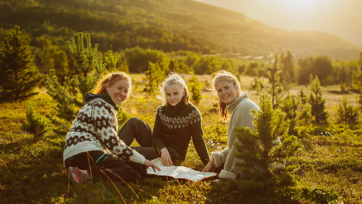 Three women sitting on the grass under the evening sun