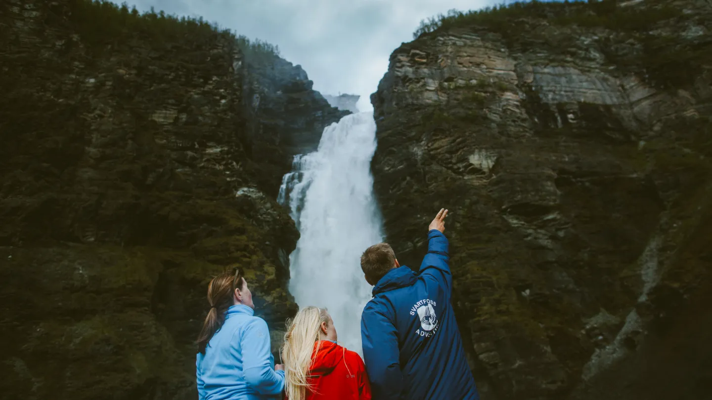 Three people looking at a waterfall (Mollisfossen)