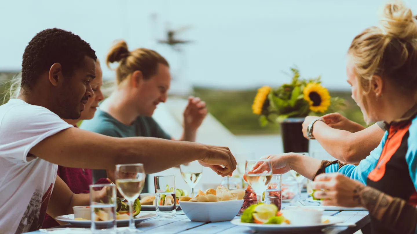 En sommerdag på bryggen, spiser lokal mat med venner rundt et bord i sommervær